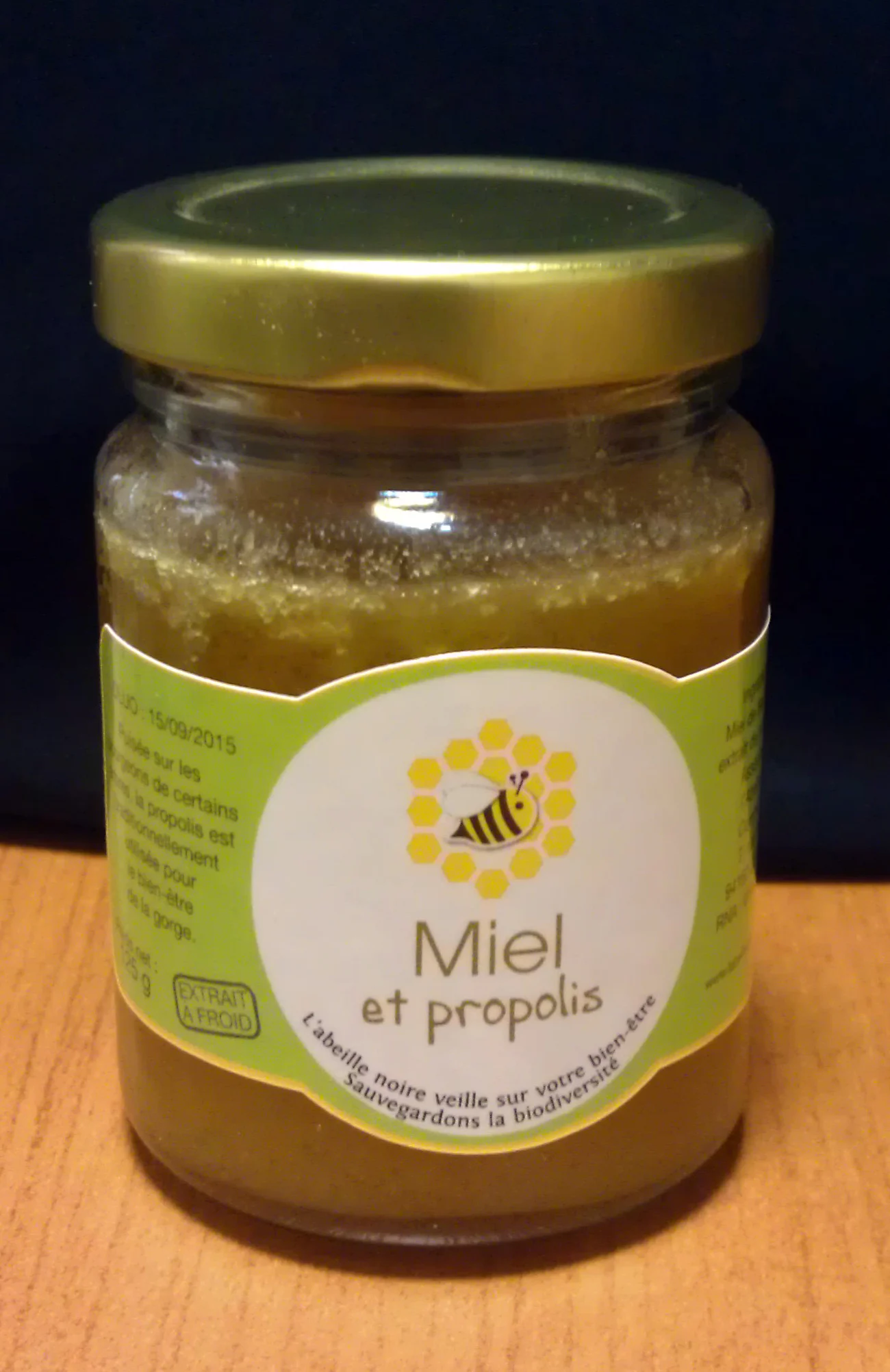 Pot de miel à la propolis, étiquette verte au logo de l'association.
