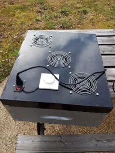 Déshydrateur peint en noir posé sur une hausse, avec ses ventilateurs, le variateur et le câble.