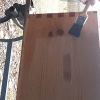 Corps de ruche Dadant en bois brut aux angles assemblés en créneaux, avec un pinceau.