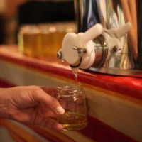 Miel coulant du robinet d'un maturateur dans un pot en verre.