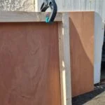 Angle de deux panneaux de contreplaqué maintenus par un serre-joint.