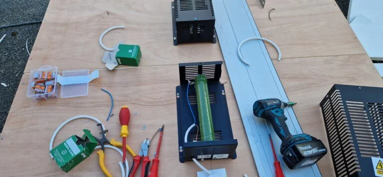 Chauffage de boîtier, câbles, borniers et outils étalés sur un établi.