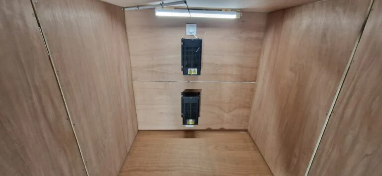 Intérieur du caisson en contreplaqué, avec le chauffage fixé au fond et une réglette lumineuse.